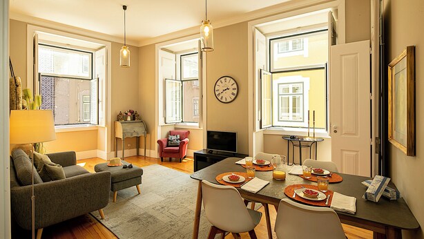 Una sala de estar moderna con un sofá, una mesa de comedor para dos personas y un televisor.
