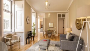 Una sala de estar moderna con un sofá gris, un reposapiés y un comedor con una mesa y sillas.