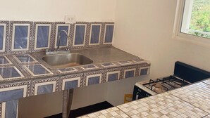 Una cocina con un lavamanos, salpicadero de azulejos y una ventana.