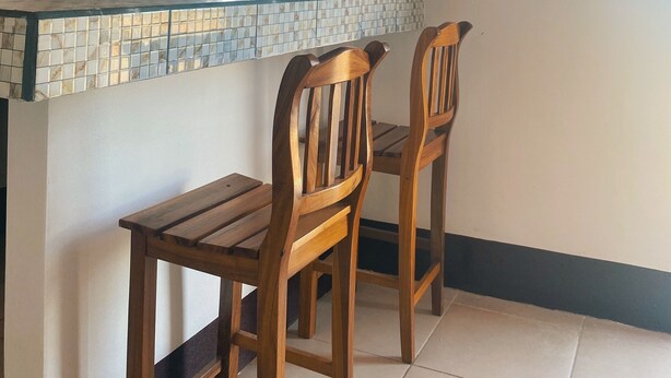 Una cocina con salpicadero de azulejos, sillas de madera y una ventana sobre la encimera.