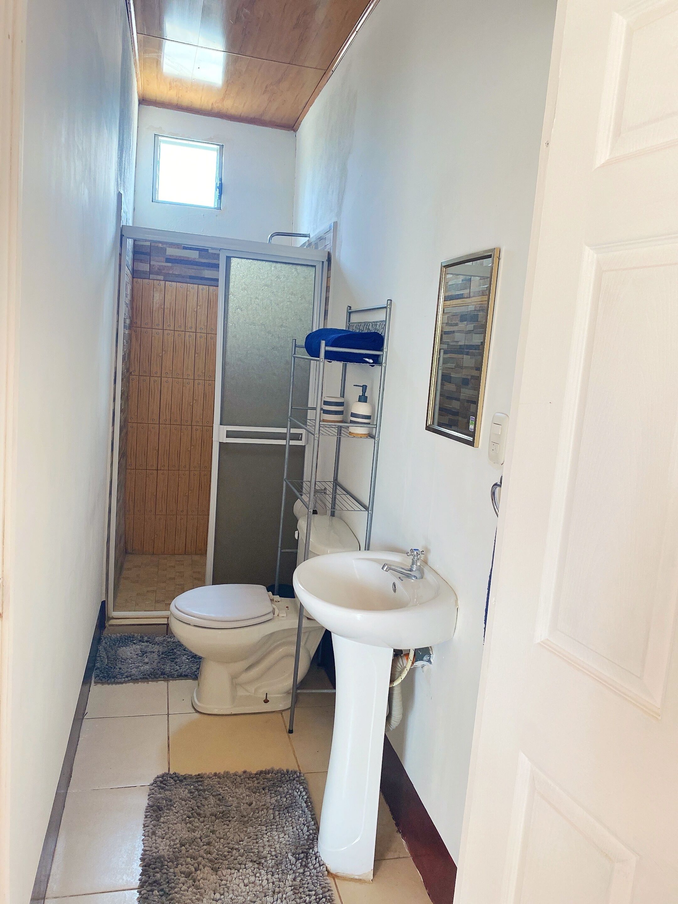 A compact bathroom with a toilet, sink, and shower.