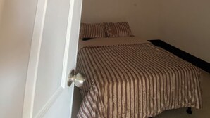 Un dormitorio con techo de madera, cama con ropa de cama a rayas y una puerta blanca.