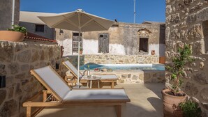 A stone-walled outdoor area with a pool, lounge chairs, and a table with drinks. - Golden Theros villa,Village Experiene in Maroulas (Maroulas)