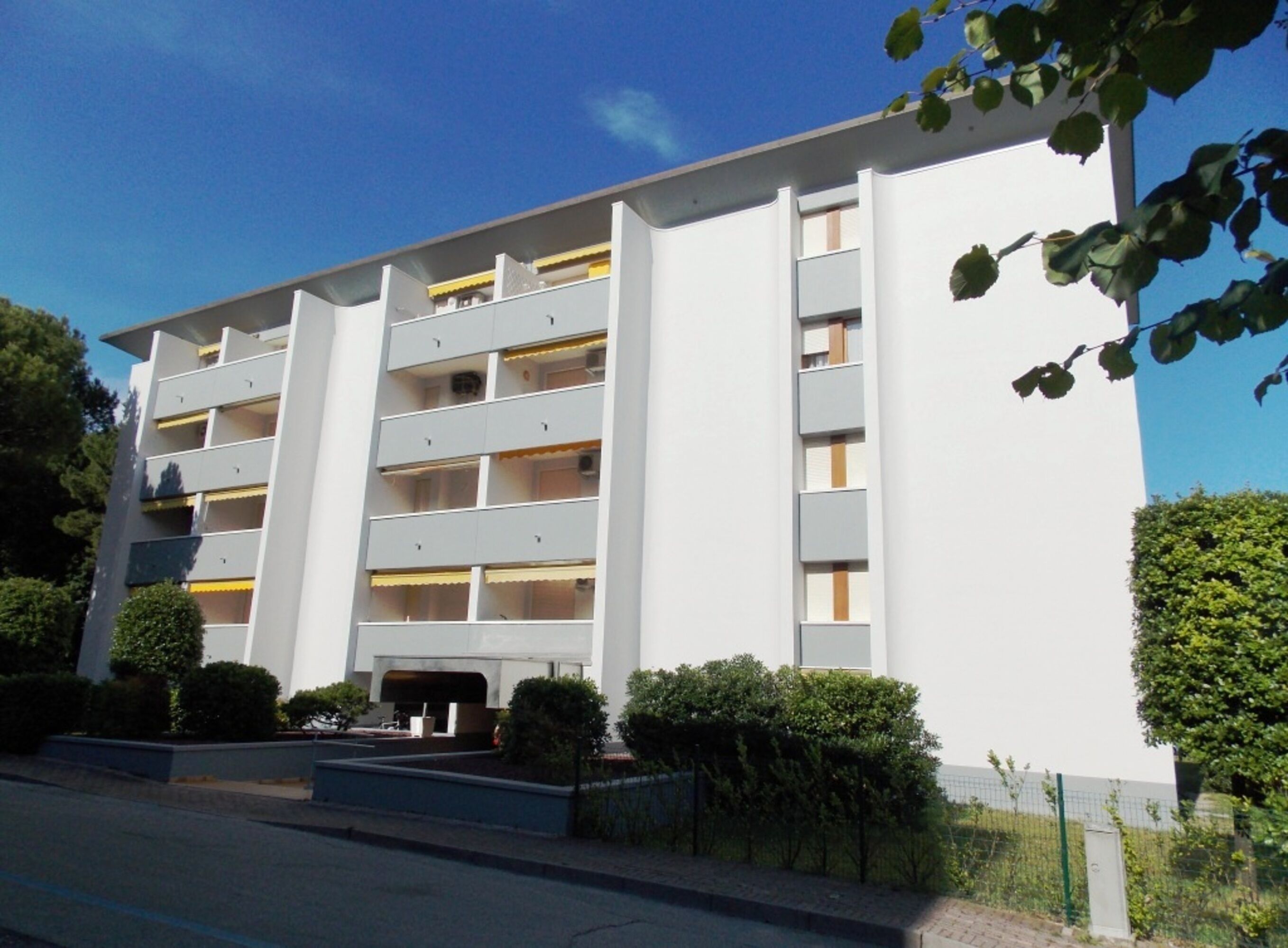 Un edificio de varios pisos con fachada plana, balcones y entrada protegida por una reja.