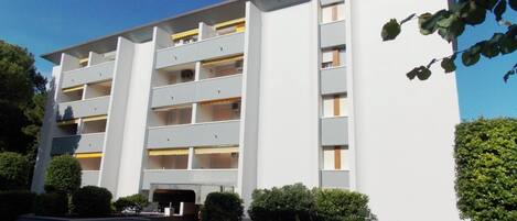 Un edificio de varios pisos con fachada plana, balcones y entrada protegida por una reja.