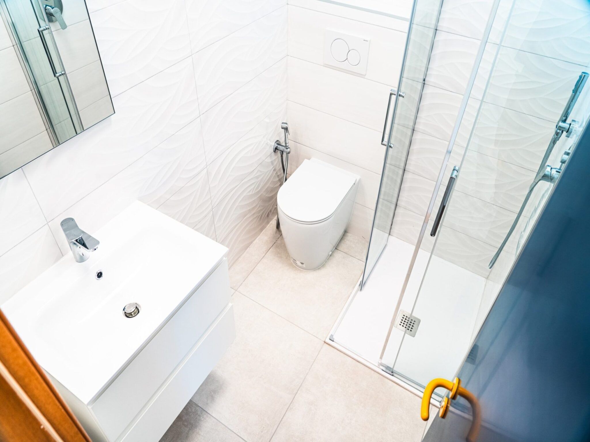 Une salle de bain moderne avec un lavabo blanc, des toilettes et une douche à parois de verre.
