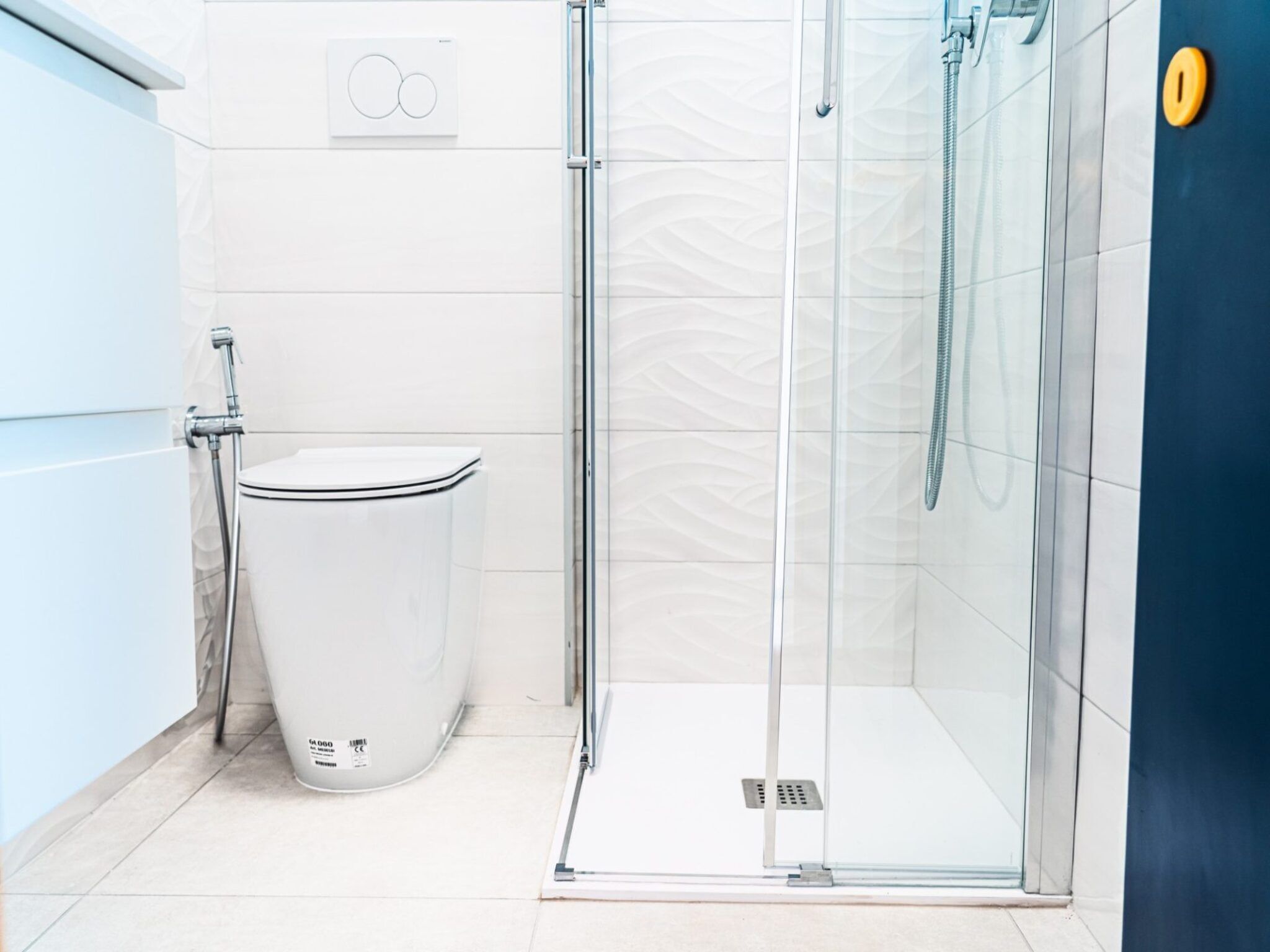 Ein modernes Badezimmer mit Duschkabine aus Glas, einer weißen Toilette und einer wandmontierten Bedienkonsole.