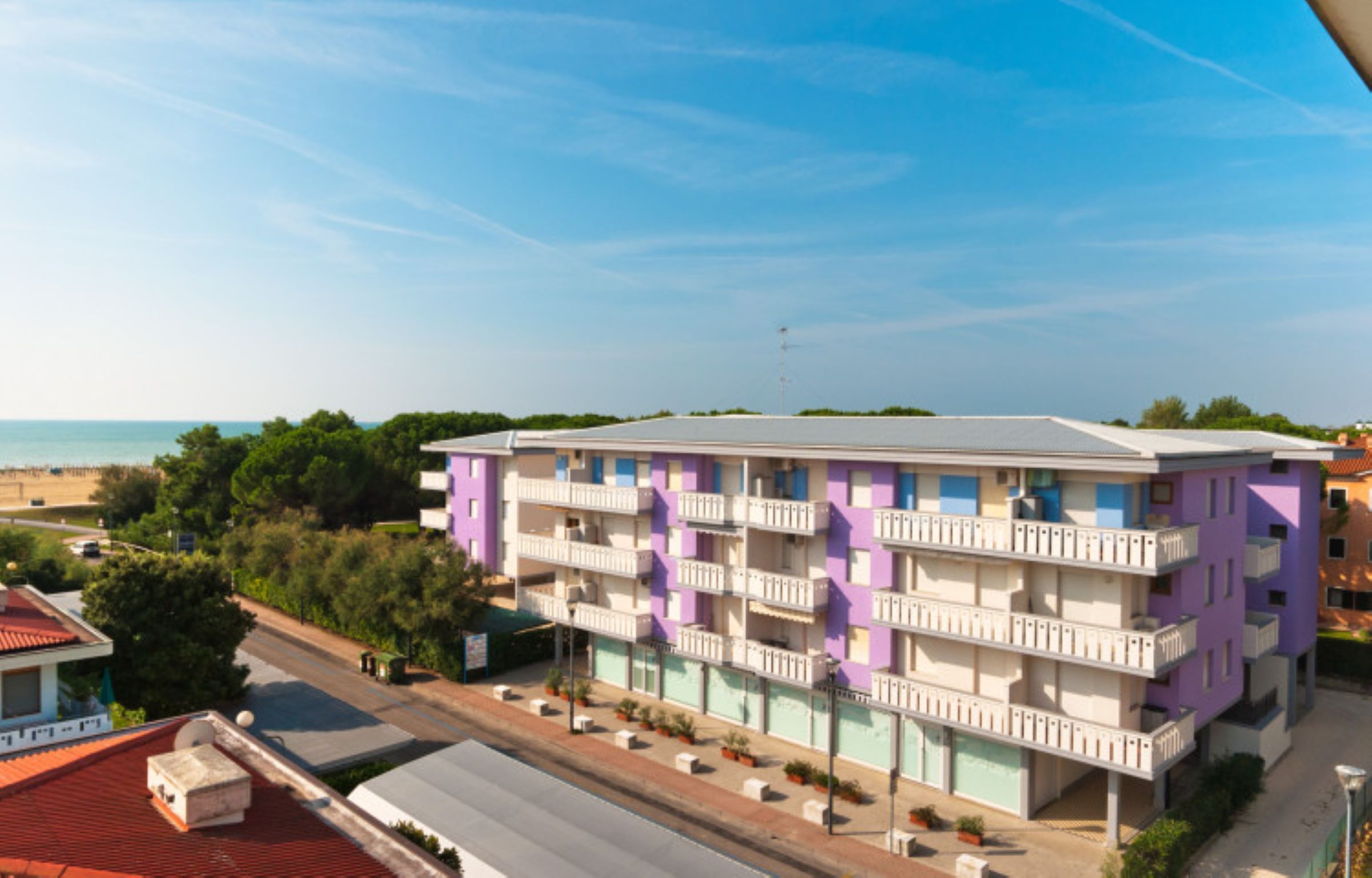 A multi-story hotel with balconies, located near a beach.