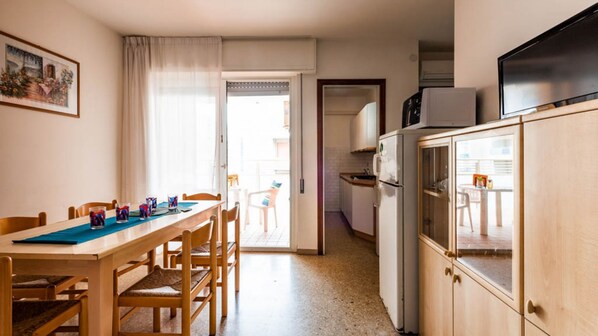 A compact kitchen with a refrigerator, microwave, and wooden cabinets. - Bright Flat Just Steps From Bibione Beach (San Michele al Tagliamento)