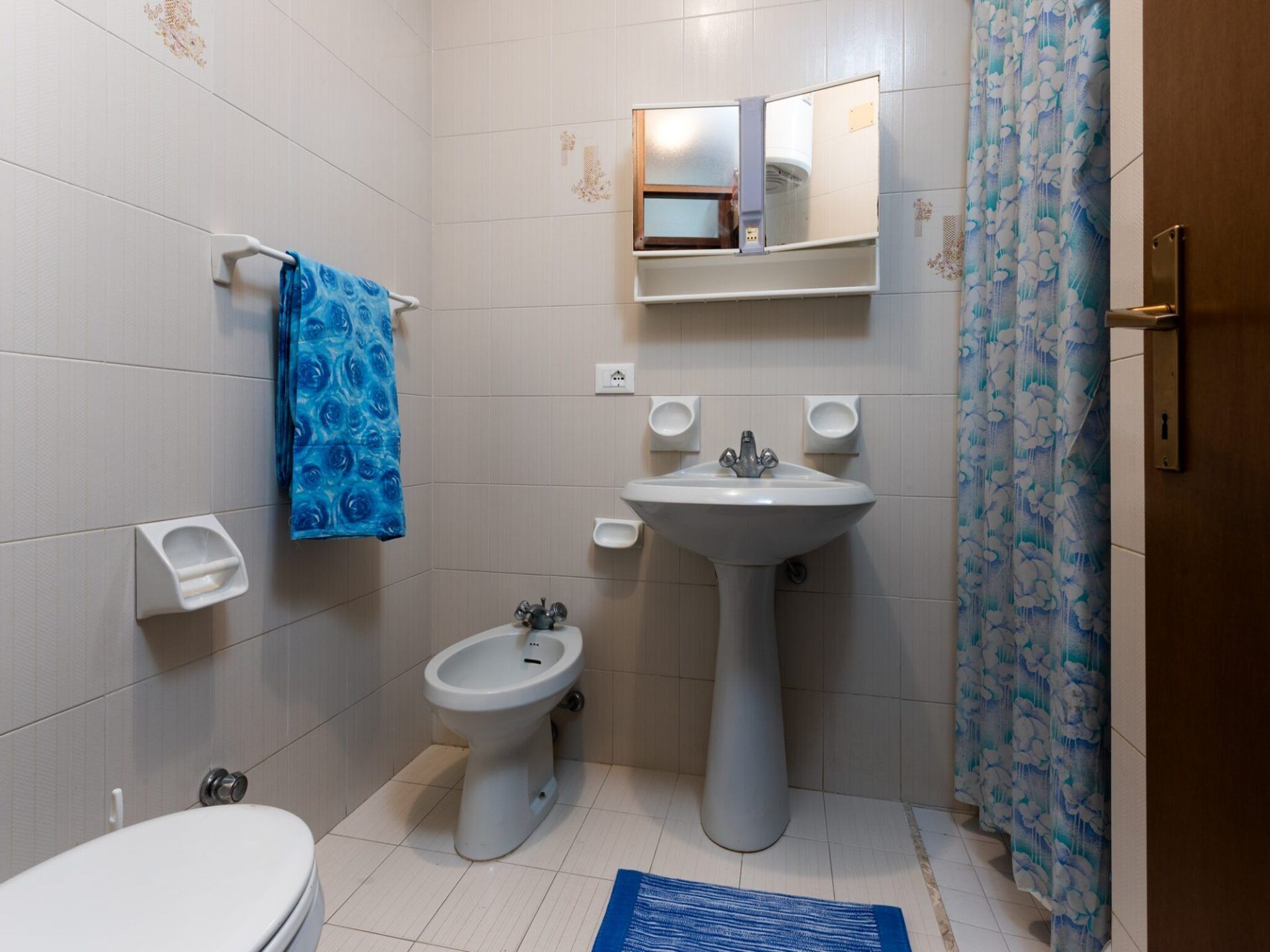 Une salle de bain comprenant des toilettes, un bidet, un lavabo et un miroir au-dessus du lavabo.