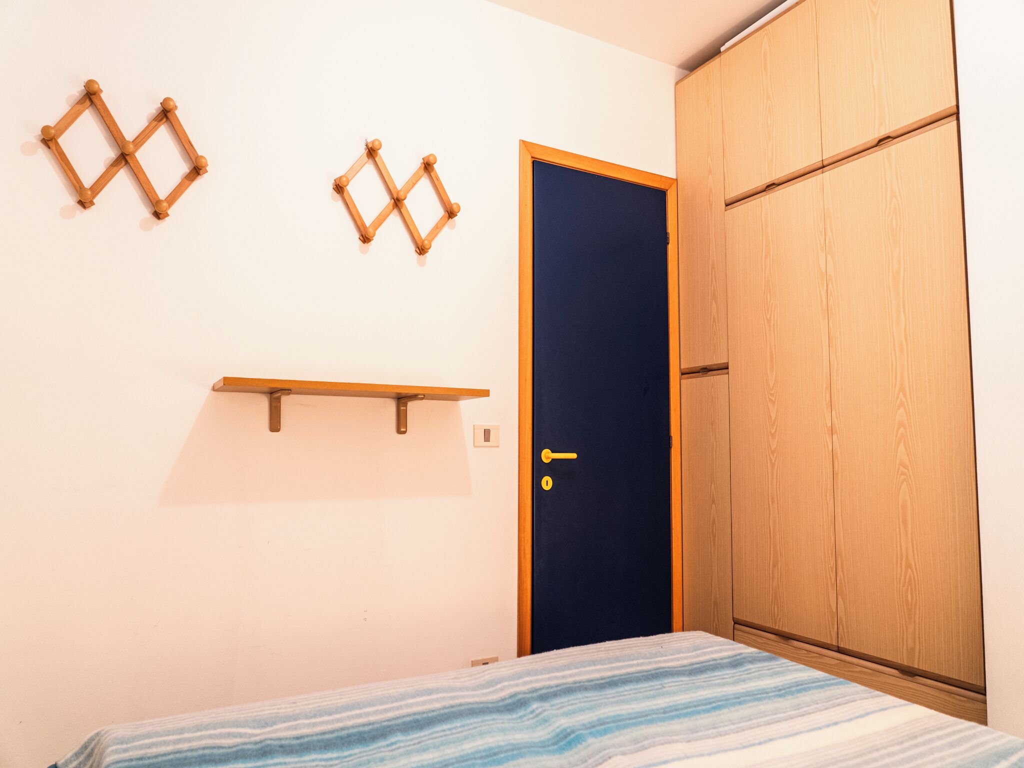 A bedroom with a bed, a wardrobe, and two wooden wall decorations.