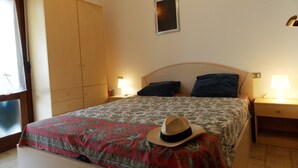 A bedroom with a bed, two bedside lamps, a wooden wardrobe, and a single wall-mounted picture. - Flat With Parking Only 100m From the Beach (San Michele al Tagliamento)