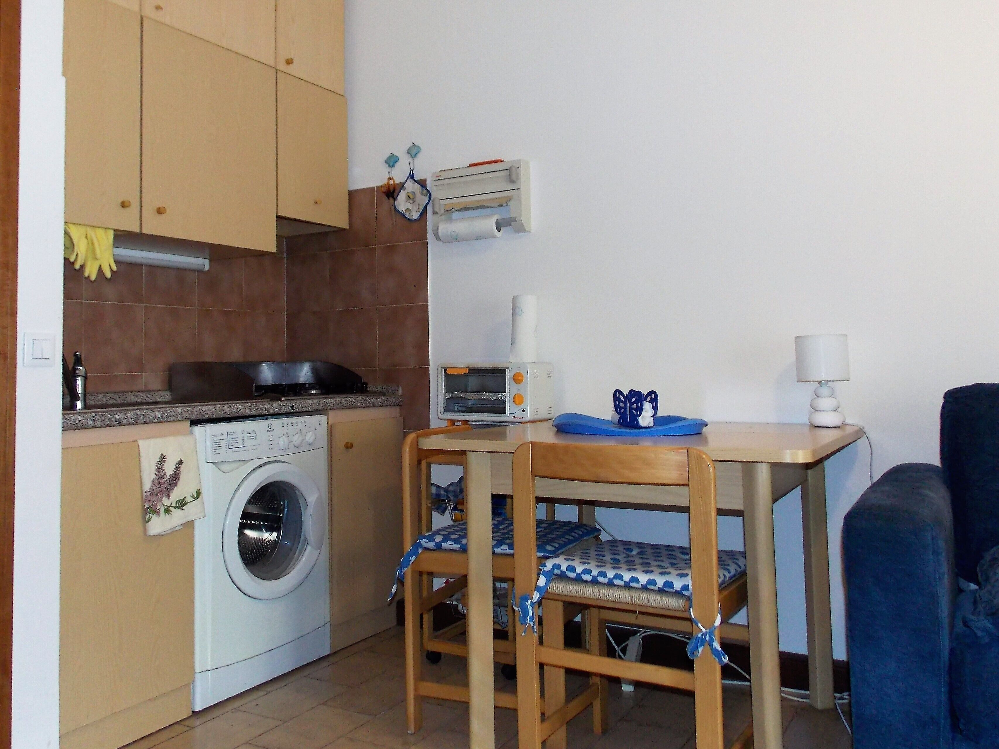 A compact kitchen with a washing machine, a toaster, and a table with chairs.
