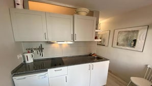 A compact kitchen with white cabinets, a built-in oven, and a sink.
