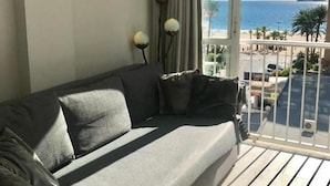 A balcony with a grey sofa, a view of the sea, and a railing.