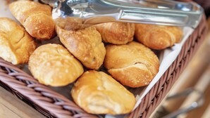 Ein Korb voller goldbrauner Backwaren, vermutlich Croissants, mit einer Zange darauf.