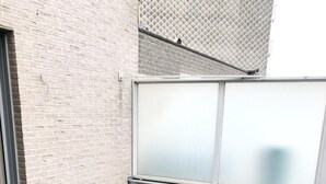 A rooftop deck with a wooden floor, a white brick wall, and a frosted glass window.