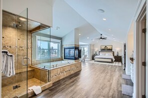 A spacious bathroom with a glass-enclosed shower, a large bathtub, and a vanity with a mirror.