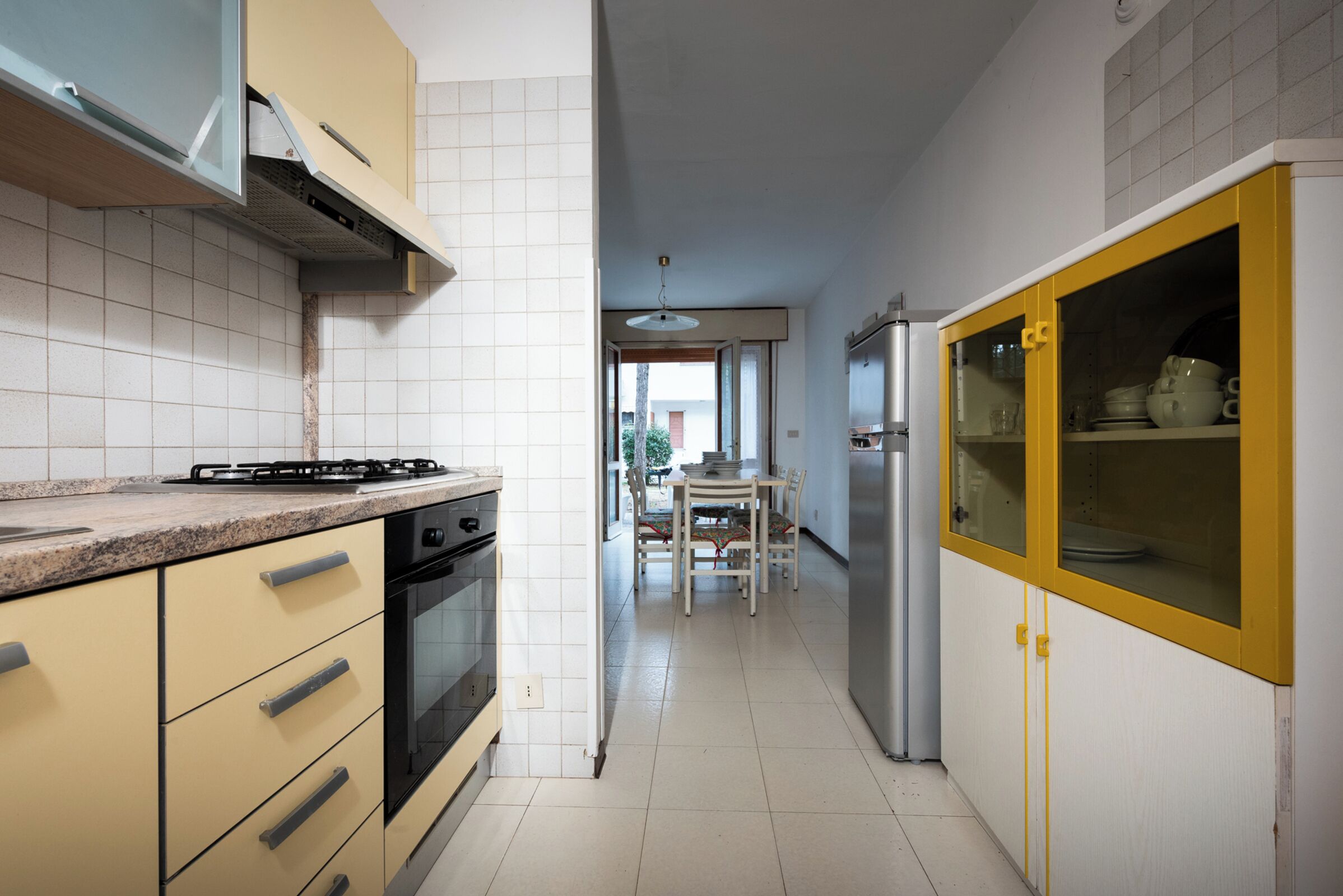 A kitchen with a gas stove, oven, and a yellow cabinet with glass doors.