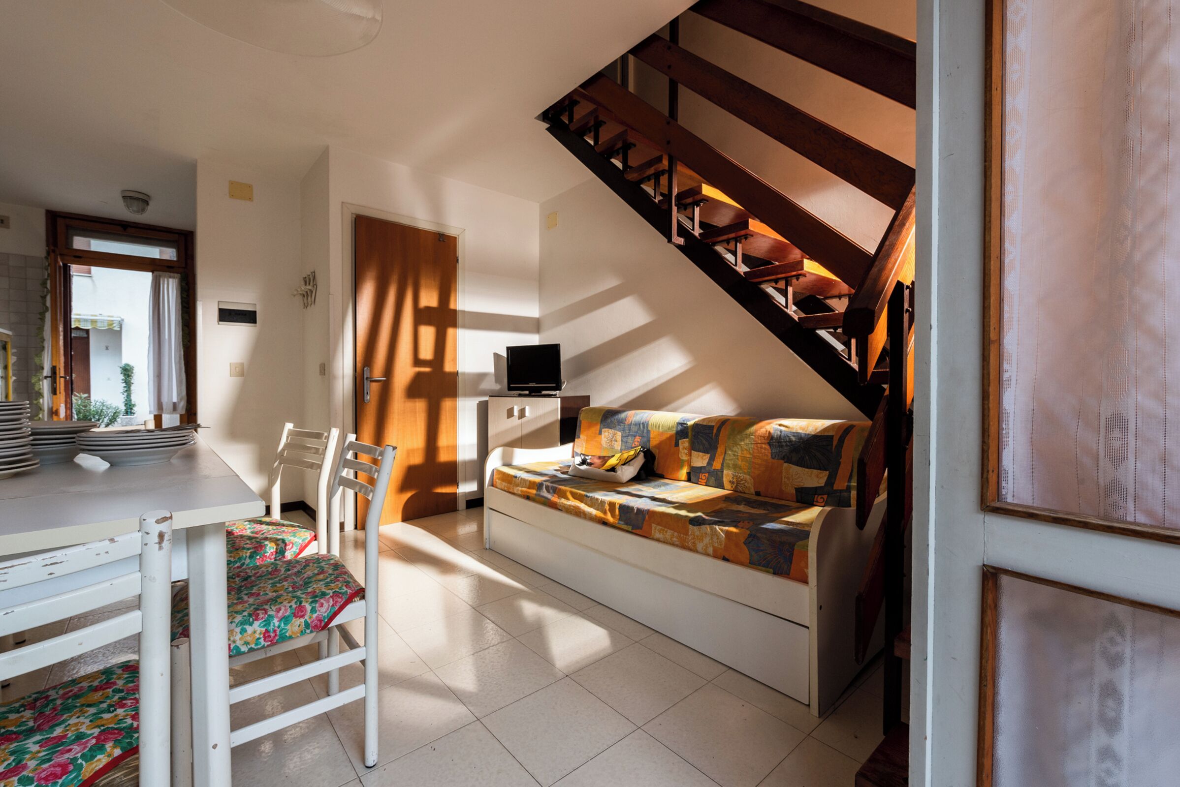 A cozy room with a sofa, a dining table with chairs, and a staircase.