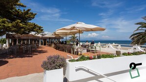 An outdoor dining area with tables and umbrellas overlooking the sea. - Hotiday Room Collection - Circeo (San Felice Circeo)