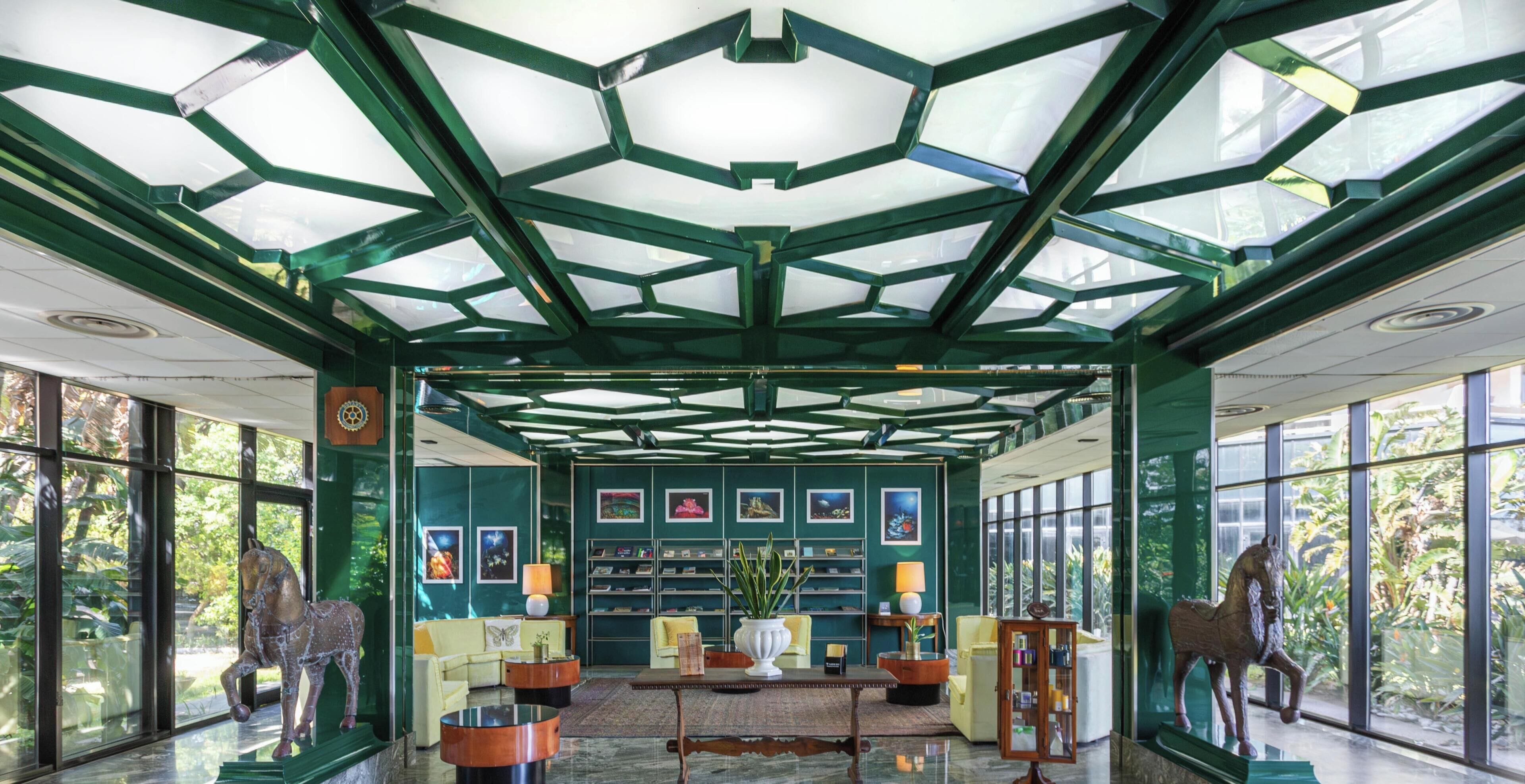 Un hall d’entrée spacieux, doté d’un haut plafond, de grandes fenêtres et d’un espace salon central avec une table basse.