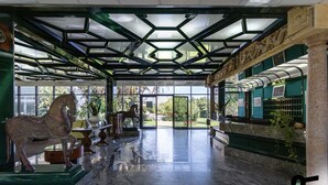 A spacious lobby with a glass ceiling, a horse statue, and a reception desk. - Hotiday Room Collection - Circeo (San Felice Circeo)