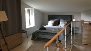 Une chambre à coucher avec un lit, une table de chevet, une lampe et une fenêtre avec des rideaux.