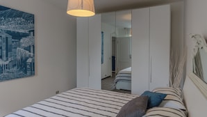 Un dormitorio con una cama, lámpara colgante, armario y un cuadro en la pared.