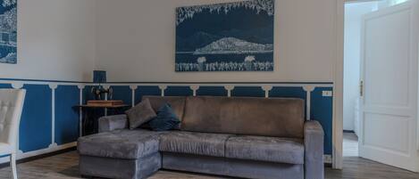 A living room with a grey sofa, a white chair, and a blue and white wall panel.