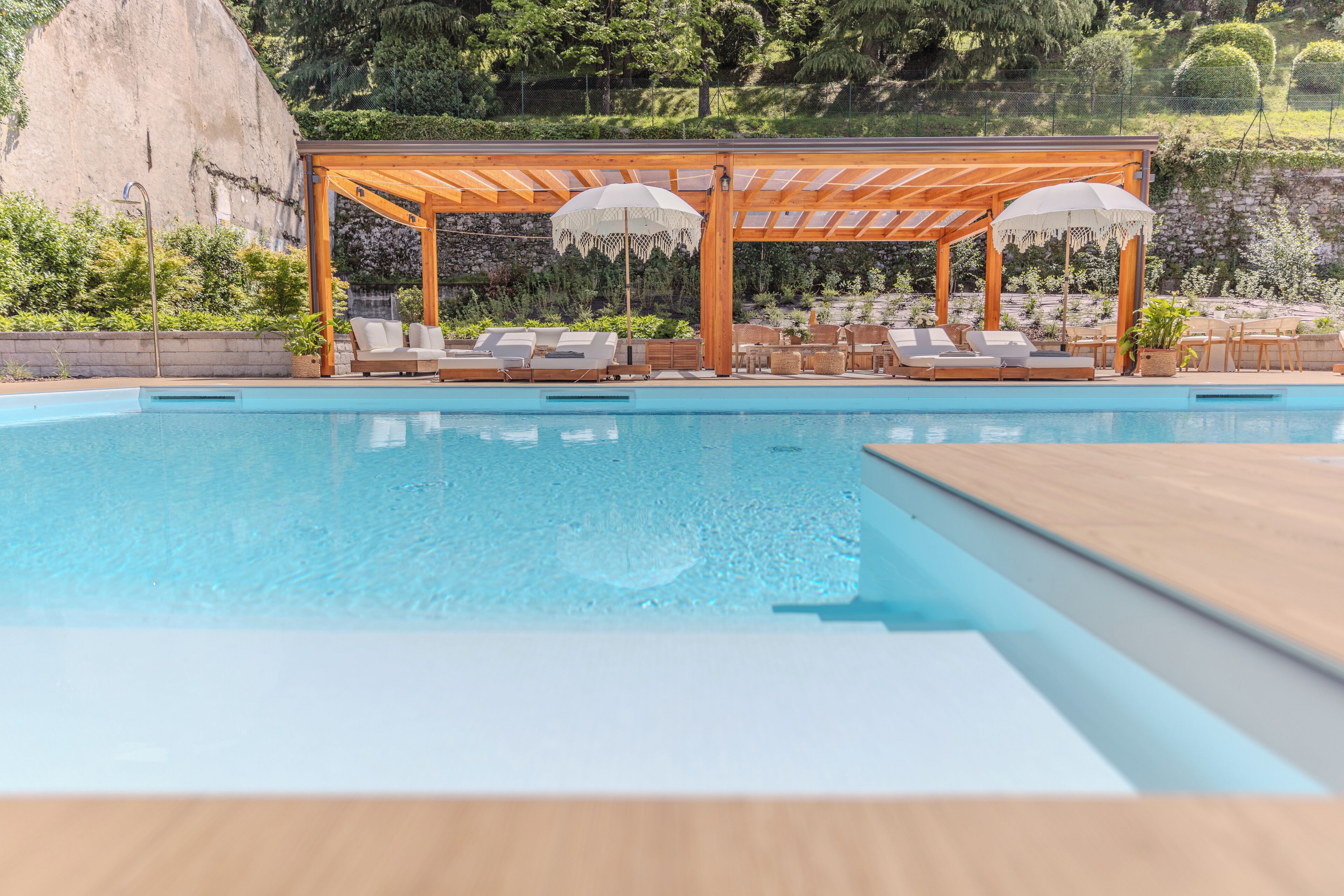 Ein Poolbereich mit einer Holzpergola und Liegestühlen.