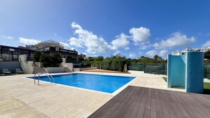 A swimming pool with a wooden deck, a restaurant named "Sexy Meat" in the background, and a clear blue sky. - ALBUFEIRA MODERN 7 WITH POOL by HOMING (Albufeira)