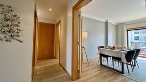A hotel room with a dining area, wooden flooring, a lamp, and a view of the outside. - ALBUFEIRA MODERN 7 WITH POOL by HOMING (Albufeira)