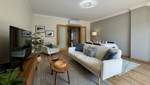 A modern living room with a sofa, armchair, coffee table, and a TV. - ALBUFEIRA MODERN 7 WITH POOL by HOMING (Albufeira)