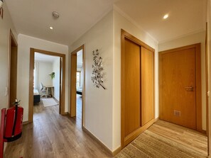 A hallway with wooden flooring, a fire extinguisher, and a wall-mounted decorative piece.