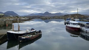 A calm harbor with boats docked, a clear sky, and mountains in the background. - Cottage 483 - Renvyle - sleeps 8 guests  in 4 bedrooms (Renvyle)