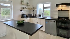 A modern kitchen with a black countertop, white cabinets, a built-in oven, and a window providing a view of the outdoors. - Cottage 483 - Renvyle - sleeps 8 guests  in 4 bedrooms (Renvyle)