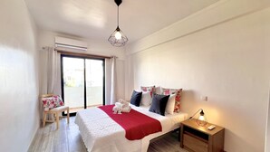 Ein Hotelzimmer mit Bett, Nachttisch, einem Fenster mit Vorhängen und einer Deckenleuchte.