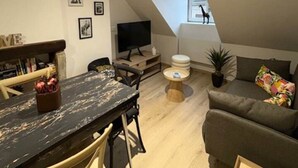 A modern loft apartment with a dining area, a sofa, a TV, and a small balcony.