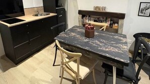 A compact kitchen with a black countertop, a microwave, and a sink. There is a dining table with two chairs and a decorative vase.