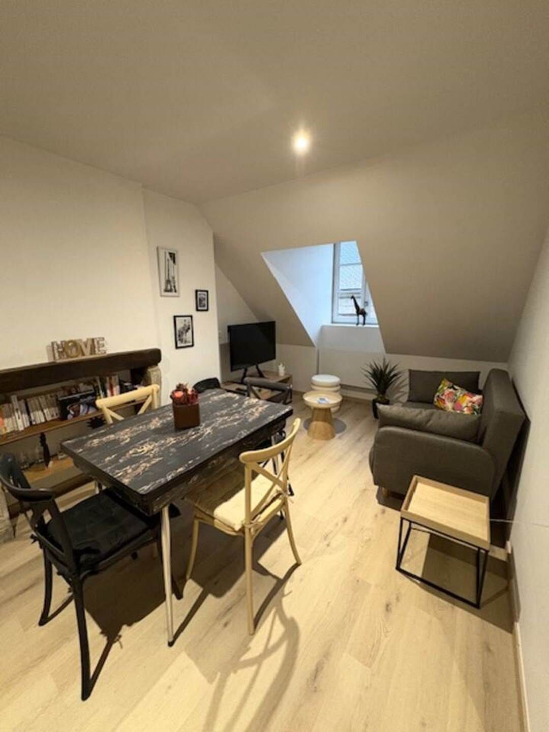 Moderni loft-tyylinen huoneisto, jossa on ruokailutila, sohva, televisio ja kirjahylly.