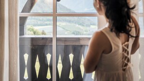 A person standing by a window with a view of a balcony and mountains.