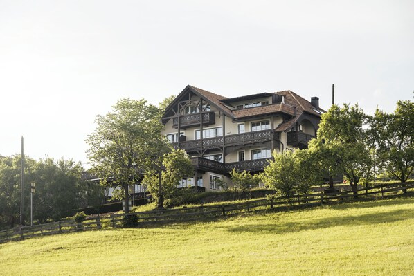A large, multi-story building with a prominent balcony and a sloped roof.