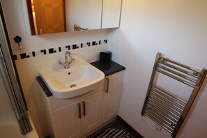 A bathroom with a sink, mirror, towel rack, and a black mat.