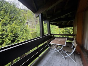 A balcony with a table and chairs, overlooking a forested area.