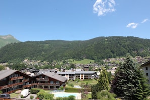 A mountain village with traditional wooden buildings, a swimming pool, and a view of the surrounding hills. - Apartment La Corniche, Central Morzine, sleeps 6 (Morzine)