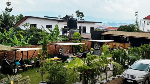 A residential area with a white building, a water tank, and a parked car. - CHALWE HOTEL APART (Kigali)