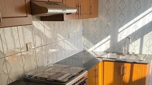 A kitchen with wooden cabinets, a stainless steel stove, and a tiled backsplash. - CHALWE HOTEL APART (Kigali)