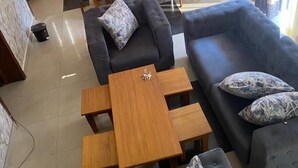 A modern living room with a sofa, two armchairs, a coffee table, and a dining area with a table and chairs. - CHALWE HOTEL APART (Kigali)