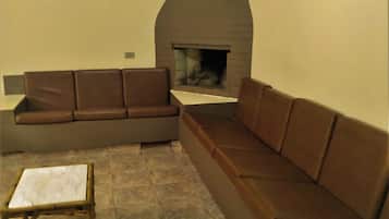 Una sala de estar con un sofá seccional marrón, una pequeña mesa de madera y una chimenea.